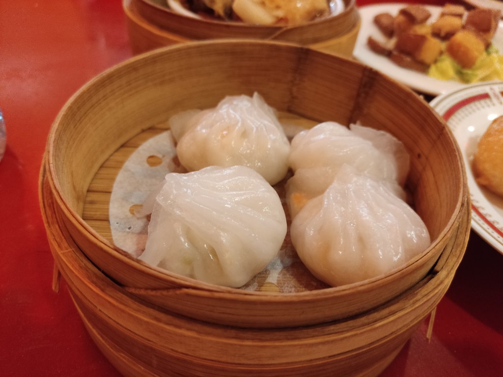 Four white steamed dumplings served in the steamer