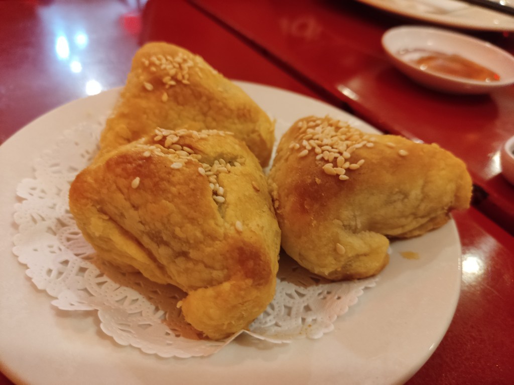 Three small triangular pastries topped with sesame seeds