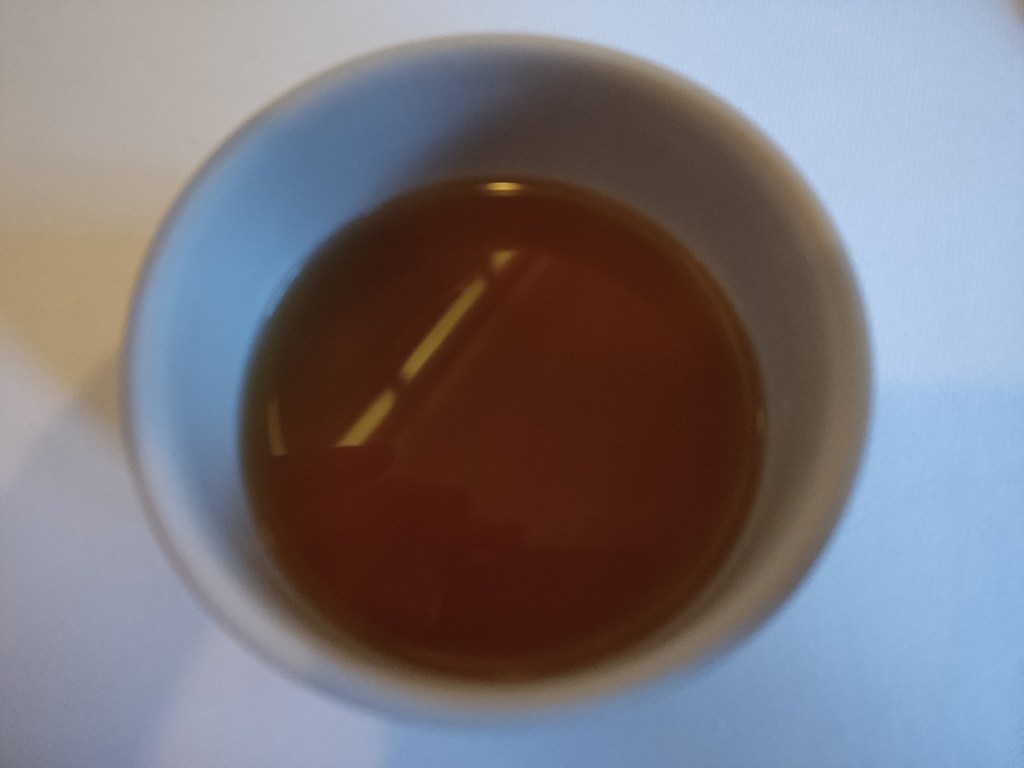 A small cup containing brown tea
