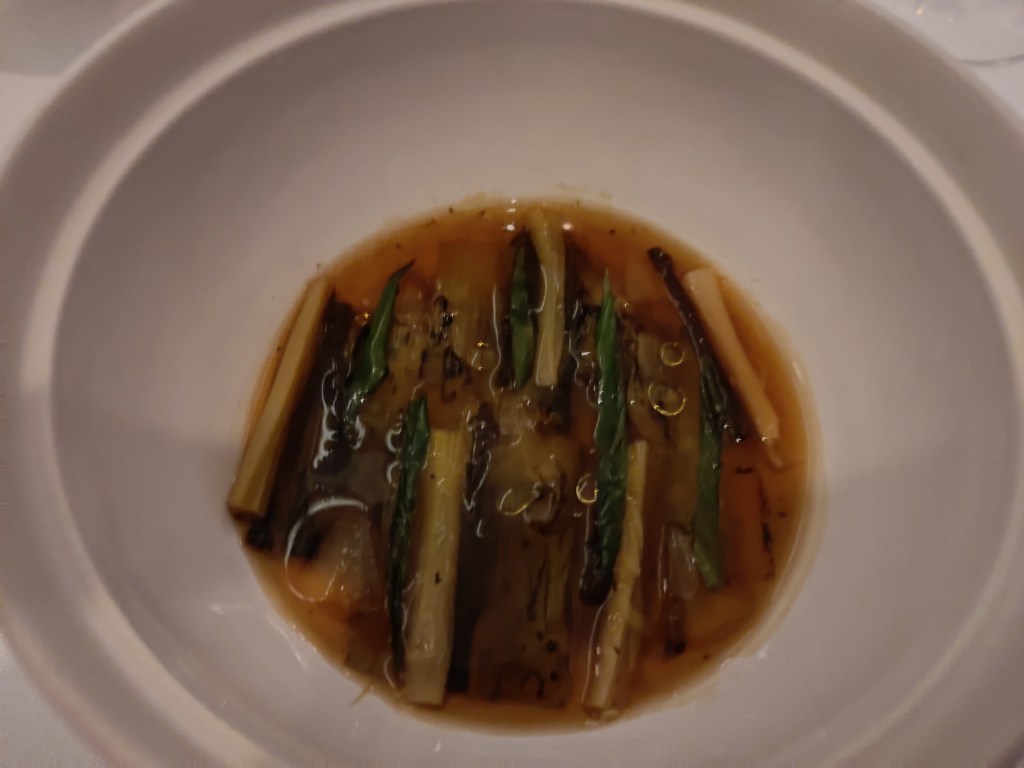 A clear broth with small leeks and spring onions