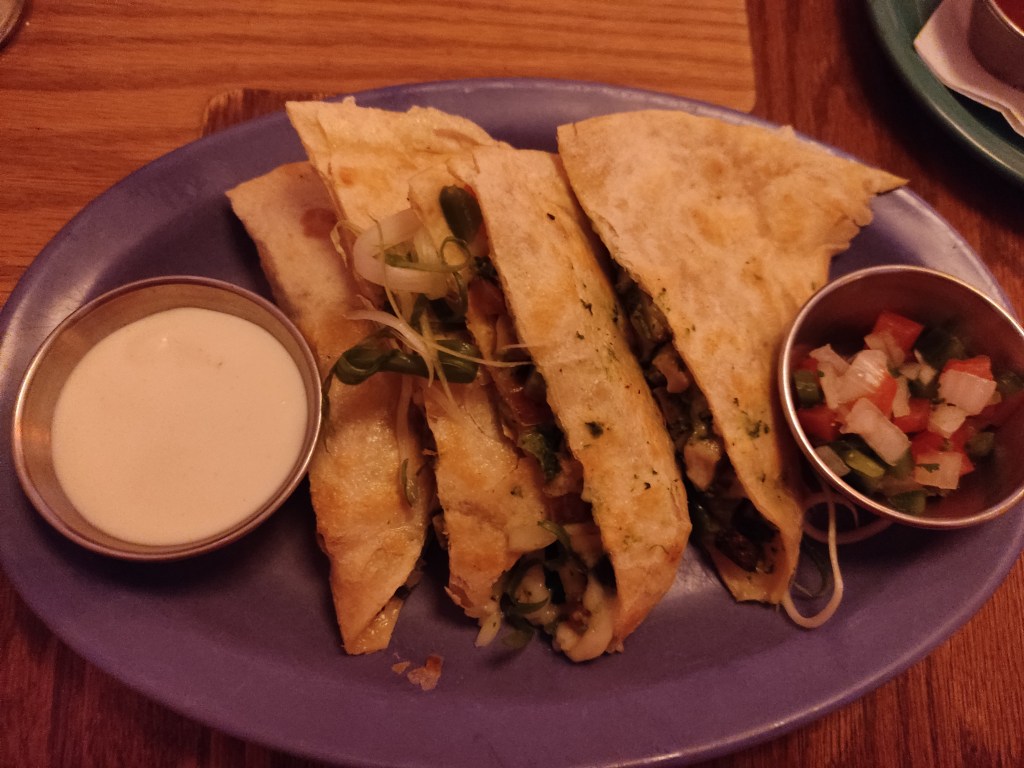 A quesadilla with salsa and sour cream on the side