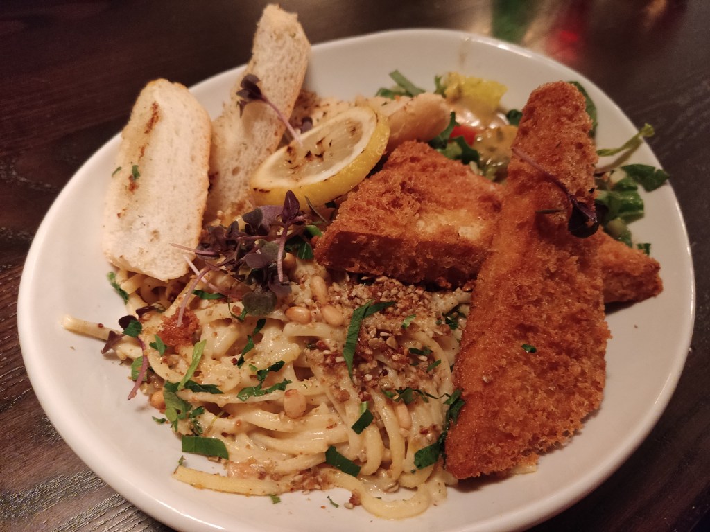A huge plate of creamy pasta, two giant slabs of tofu fried chicken, and two slices of garlic bread