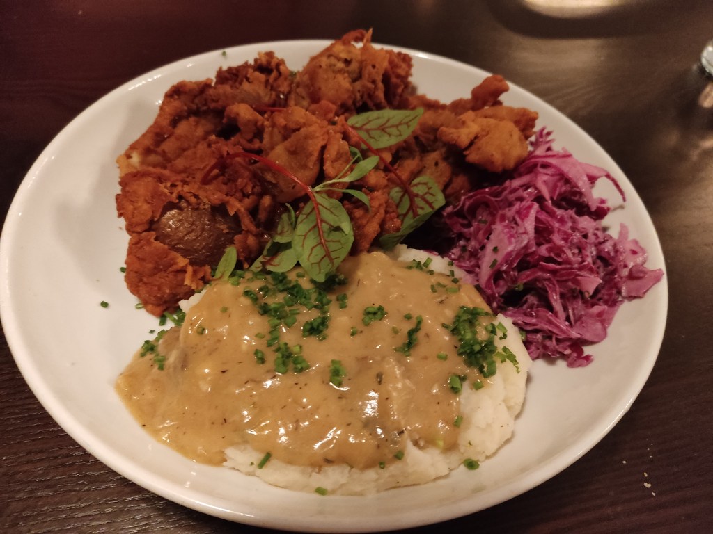 A large helping of deep fried mushrooms, a huge dollop of mashed potatoes covered in gravy and a portion of coleslaw