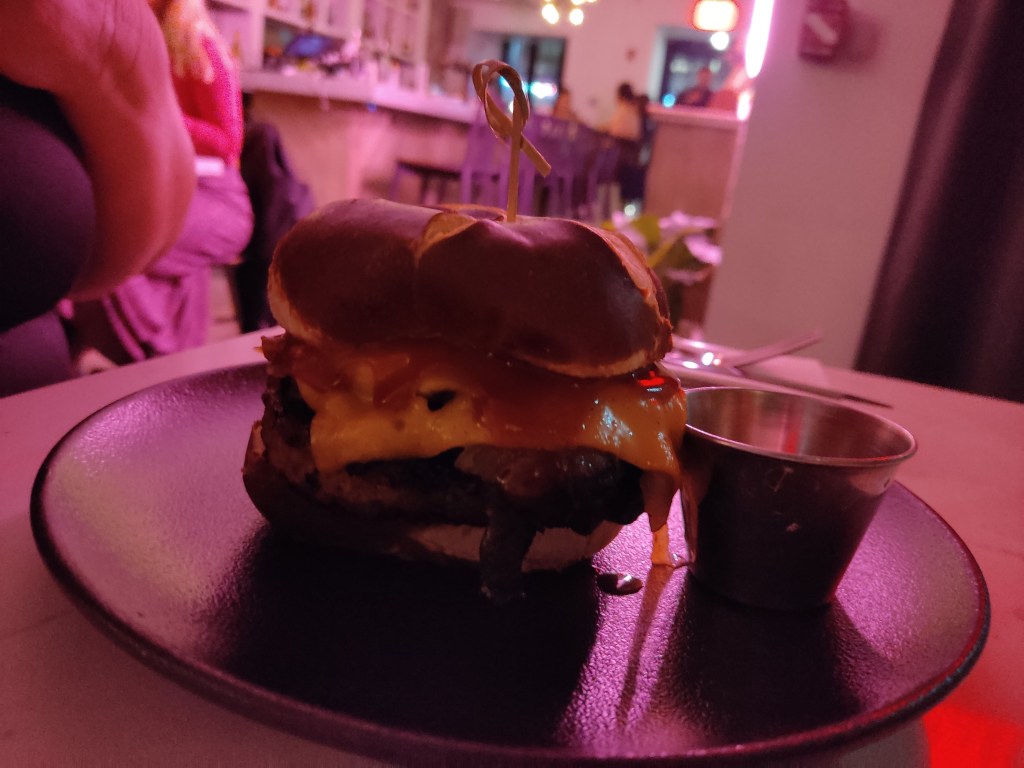 A burger in a pretzel bun with a patty, cheese, and mushrooms.