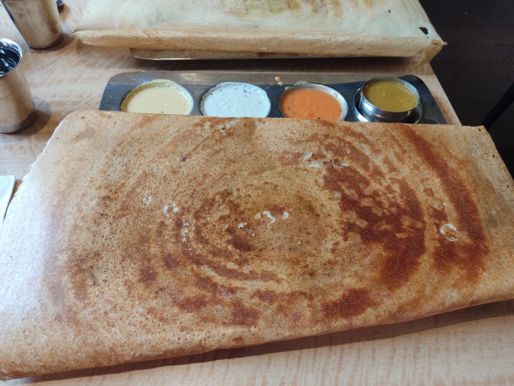 A gigantic dosa with a few dipping accompaniments