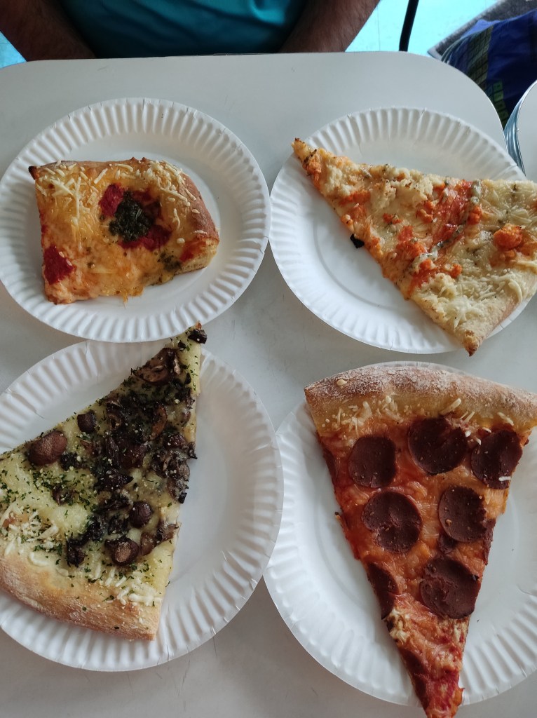 Four slices of pizza on paper plates on a tabe