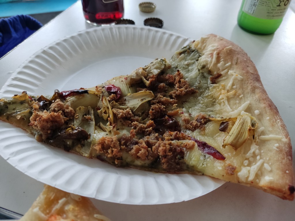 A slice of pizza topped with artichoke and meaty crumbles