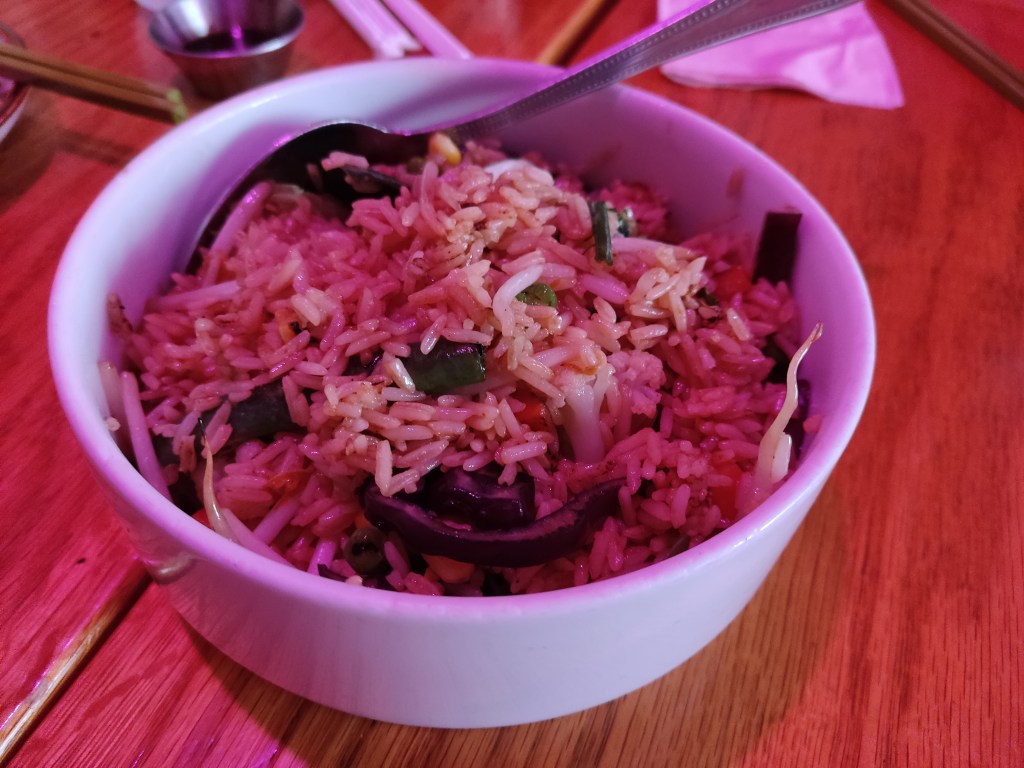 A large bowl of fried rice with some small vegetable pieces stirred through 