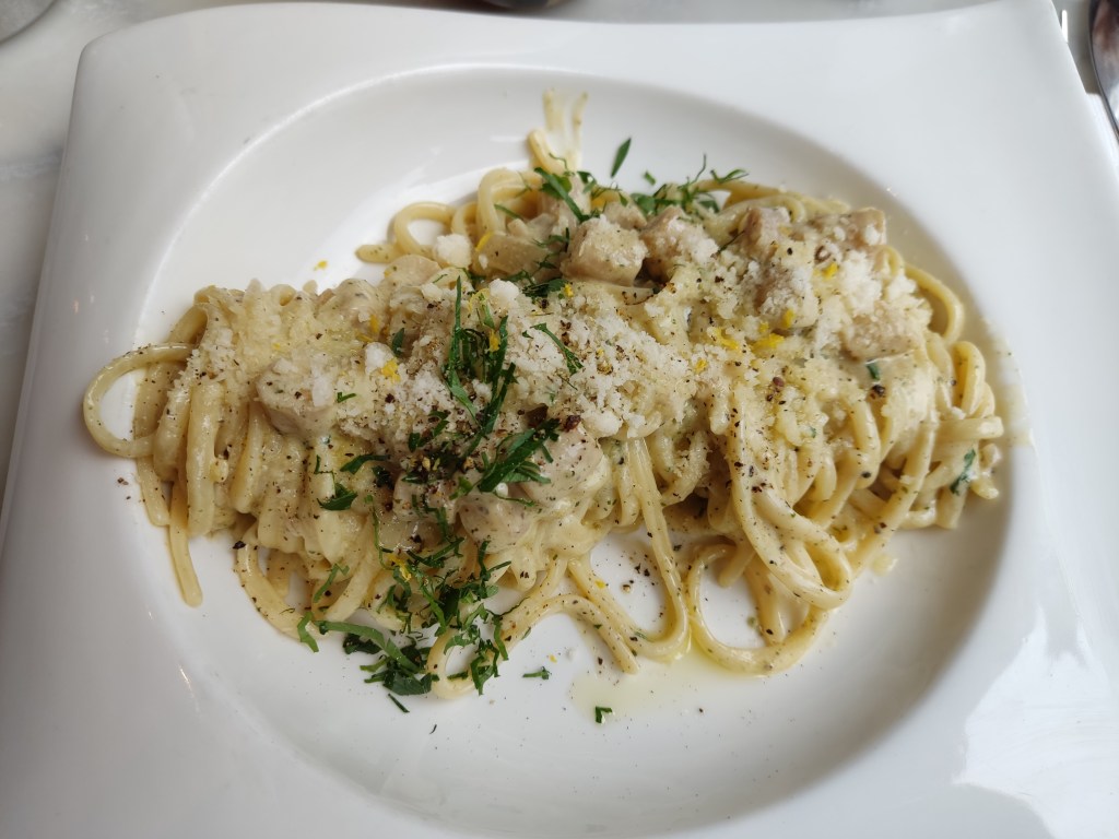 An elegant portion of pasta in a creamy sauce, topped with some mushroom pieces and herbs