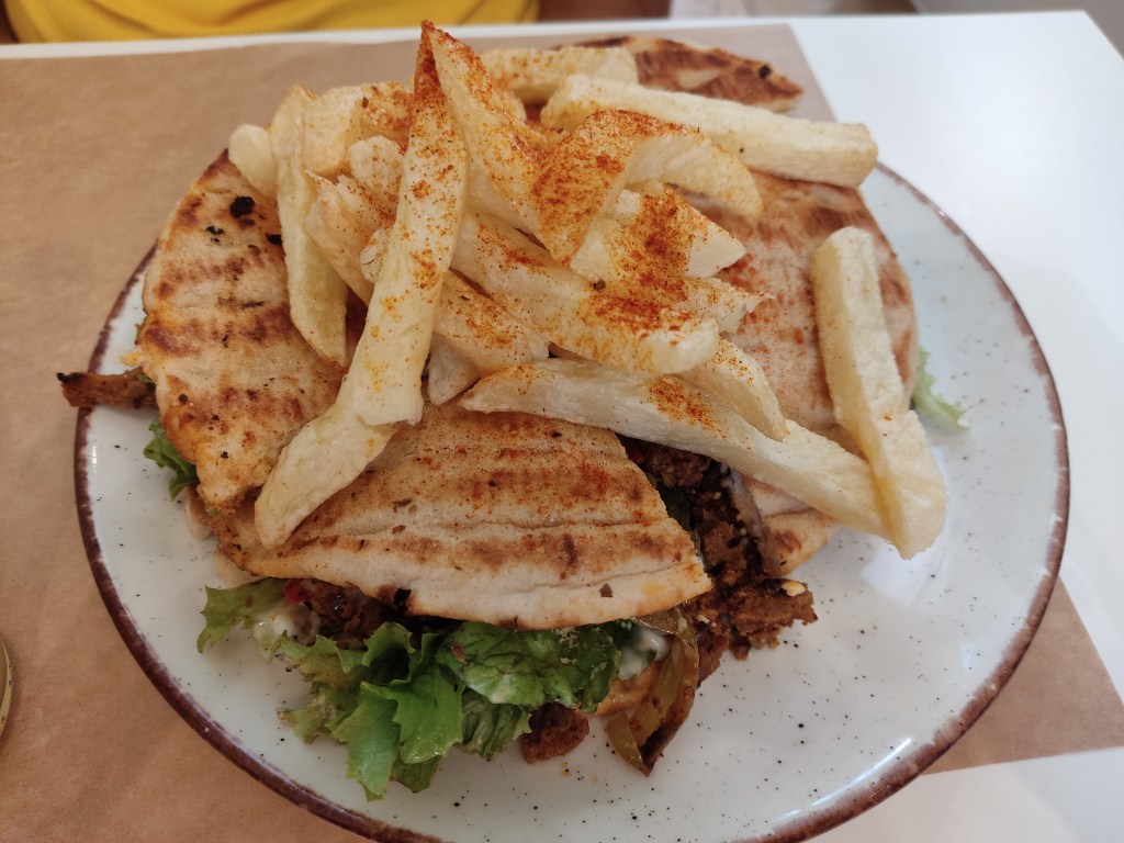 A large pita sandwich with well seasoned chips on top