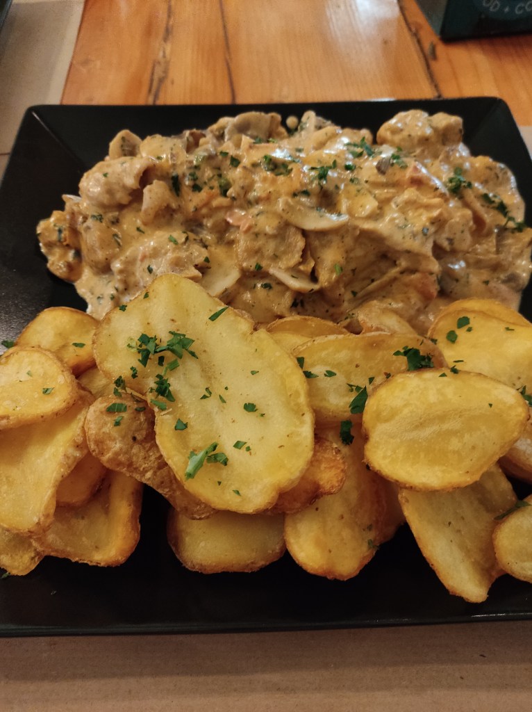 Fried potato slices and a creamy chicken dish