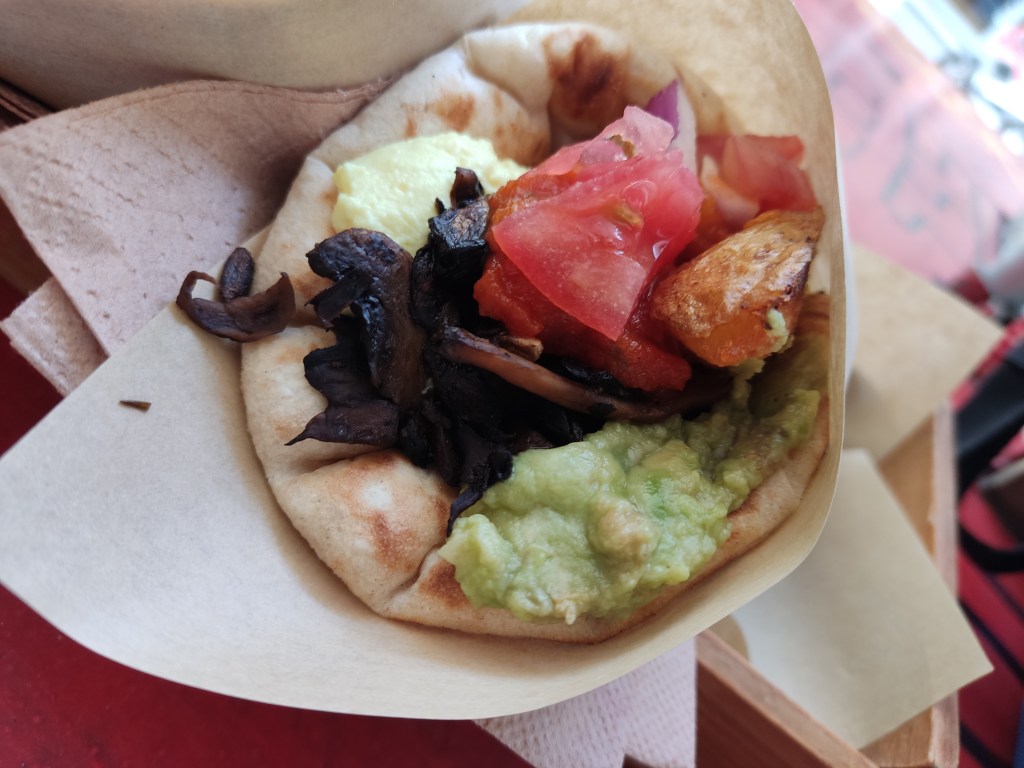A fluffy pita filled with mushrooms, avocado, salad, and potato