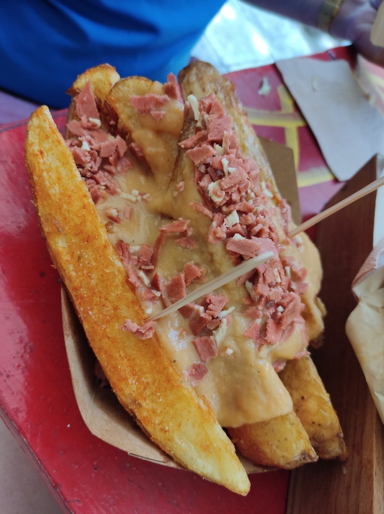 Large potato wedges covered in cheese sauce and scattered with bacon bits