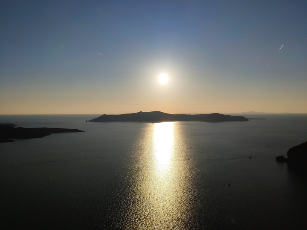 The sun setting behind a Greek island