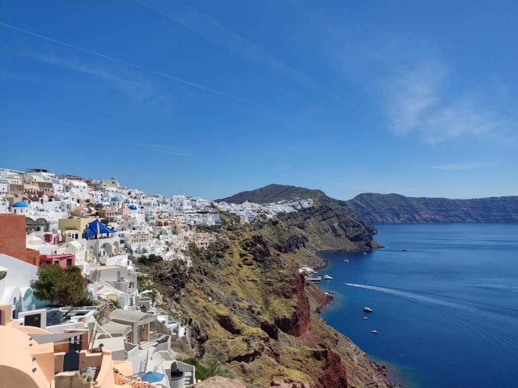 The view from Oia looking back along Santorini, with white buildings and blue sea