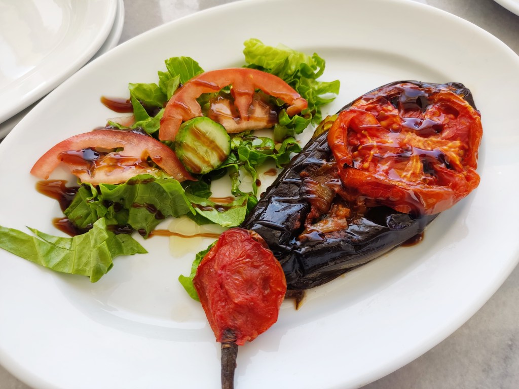 Baked aubergine with tomato and salad drizzled with balsamic vinegar