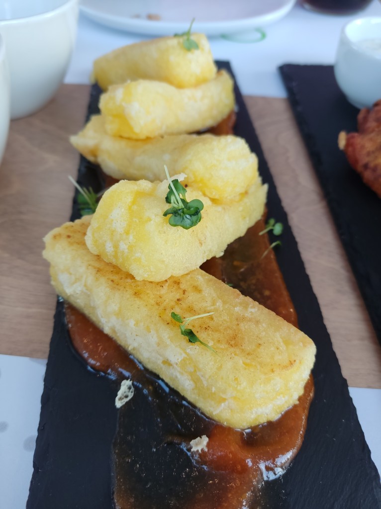 Five sticks of fried cheese on a tomato sauce