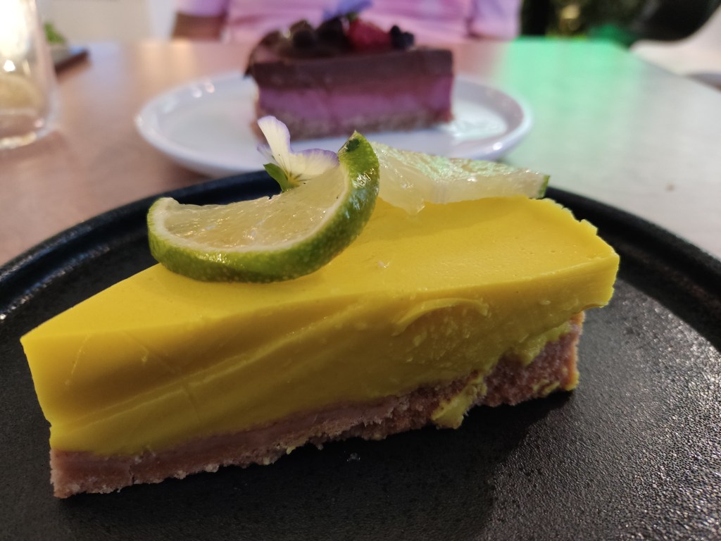 A bright yellow cheesecake topped with sliced lime