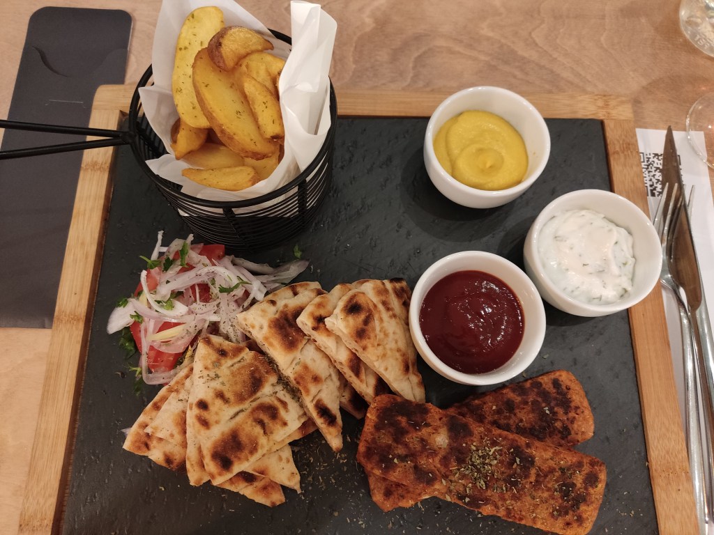 Kebab plate with potato wedges, salad, pita, sauces, and two slabs of meat