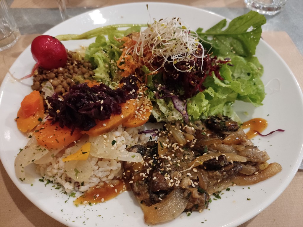 A big plate of various salad items and a piece of tart