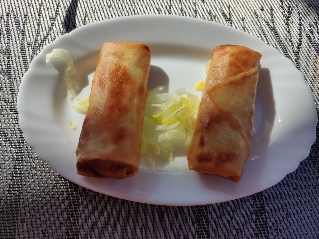 Two crispy fried spring rolls on a salad garnish