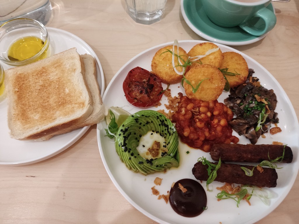 The same breakfast plate as above, with a smaller plate on the side containing two slices of toasted white bread and a pot of olive oil