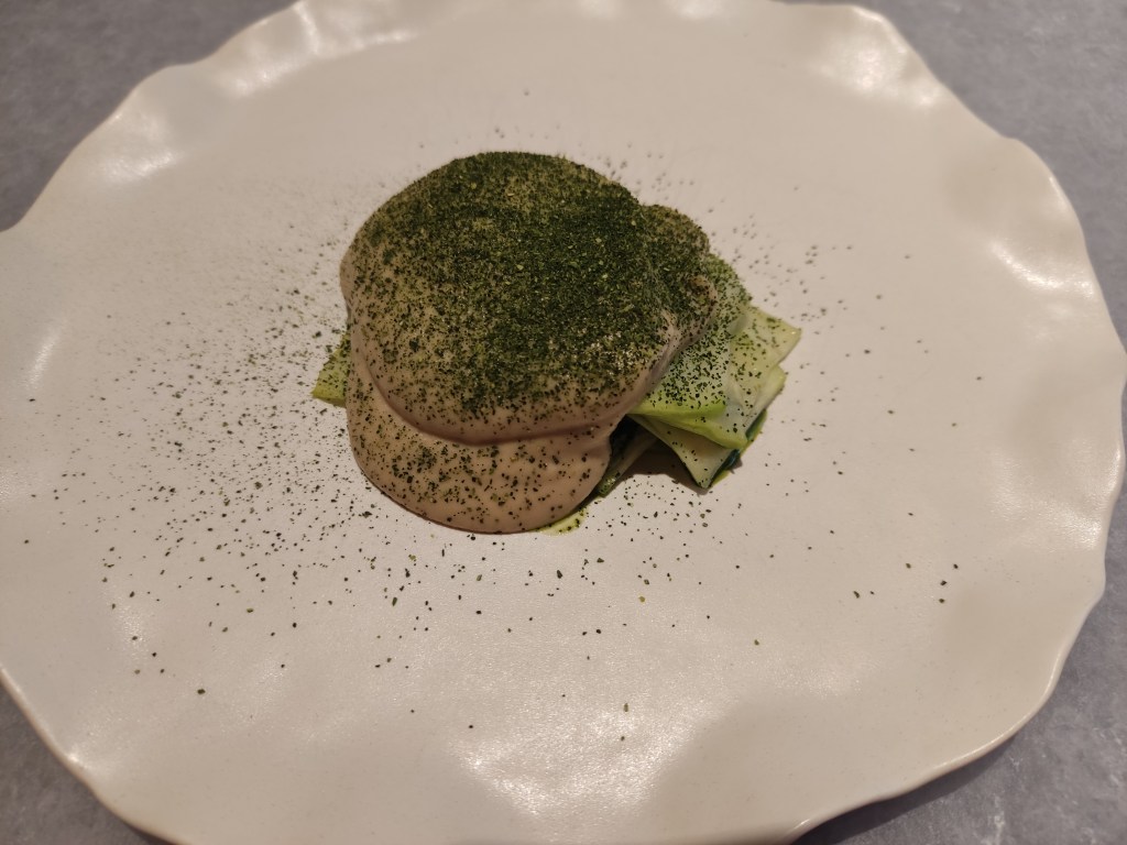 Some thin strips of courgette covered in a big scoop of sesame cream, topped with a green powder.