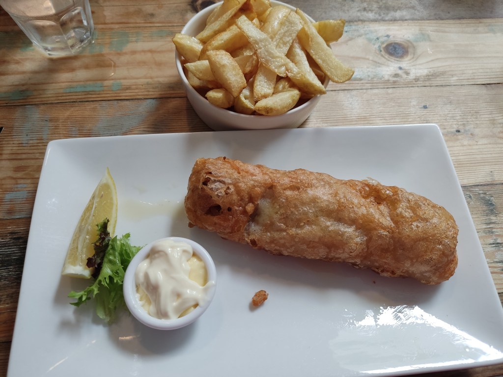 A plate with vegan fish and a bowl of chips