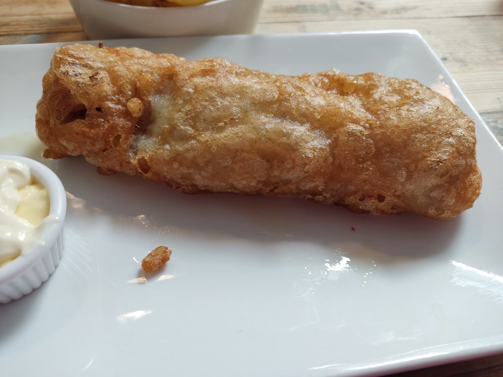 A battered vegan fish in quite a long, uniform shape.