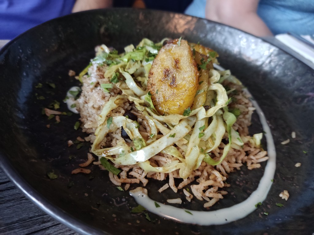 A plate of rice topped with some greens and plantain