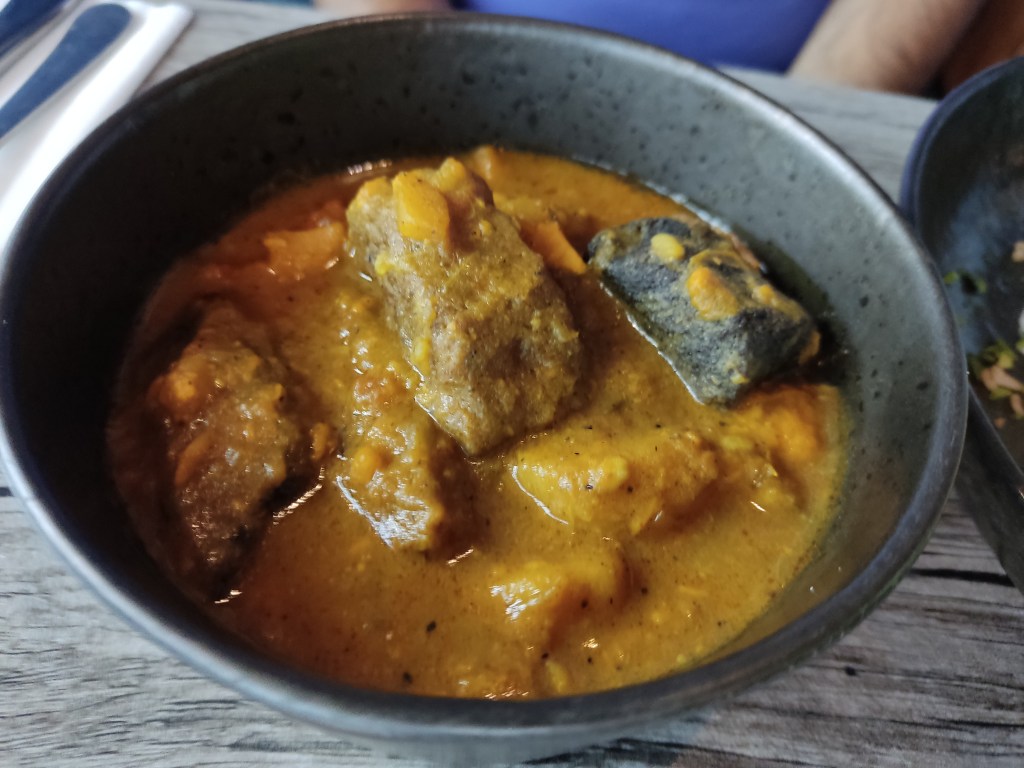 A bowl of yellow curry sauce with big chunks of mock meat and potato