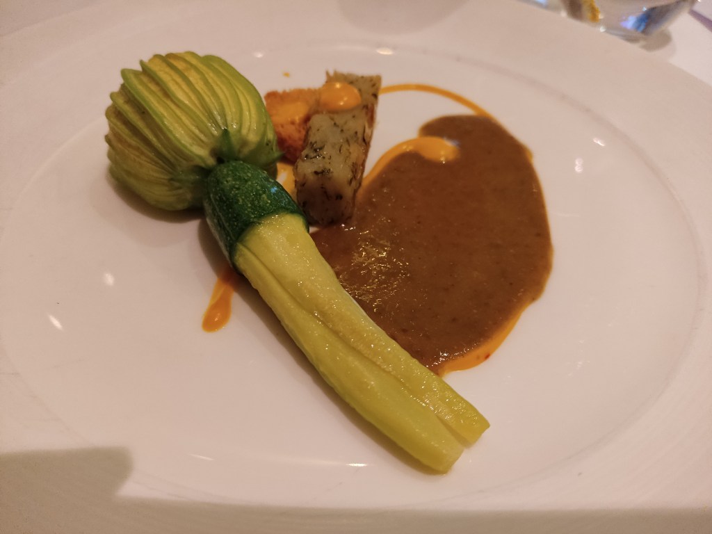 A courgette flower, brown sauce, a bit of potato and a hint of a crouton in the background