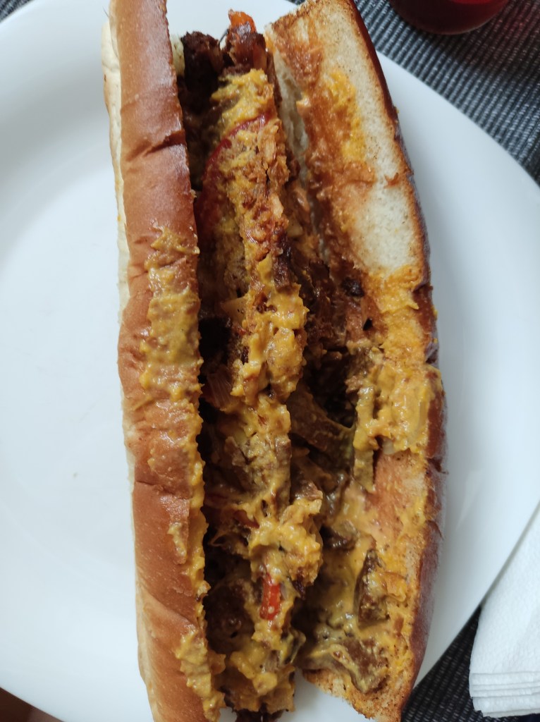 A long cheesesteak sandwich filled with seitan and cheesy sauce