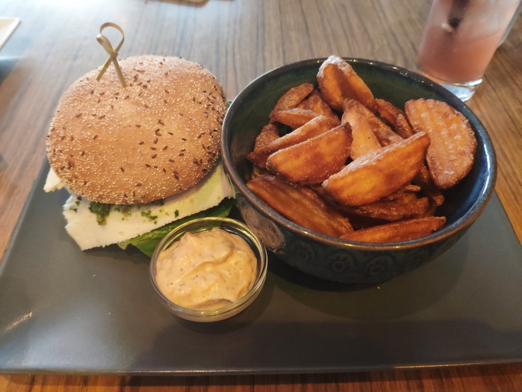 A burger, a big bowl of crinkle cut chips, and a pot of mayo.
