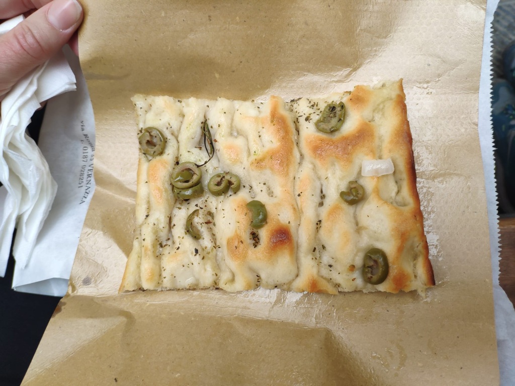 A slice of takeaway focaccia scattered with sliced green olives