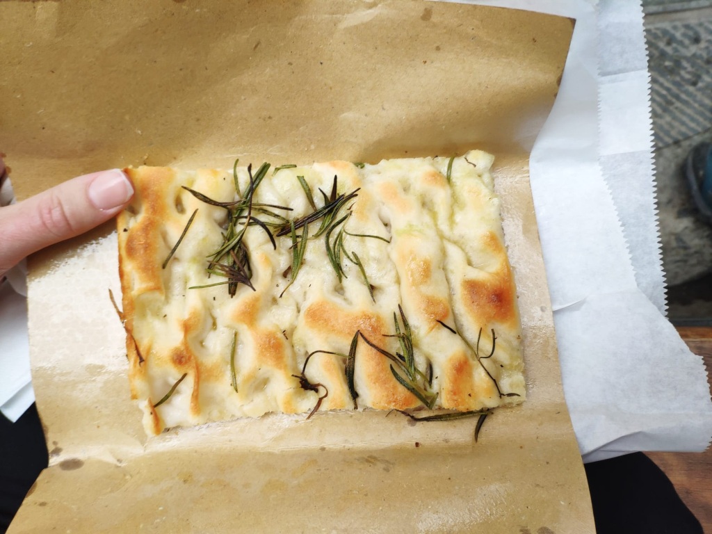 A slice of takeaway focaccia, topped with huge strands of rosemary