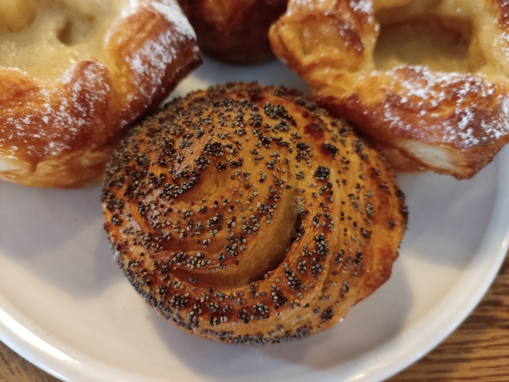 A pastry snail topped with poppy seeds.