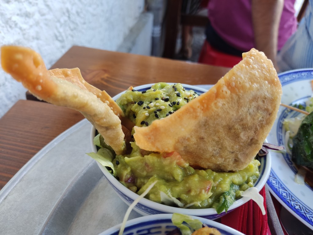 A bowl with guacamole at the top and two crispy wontons poking out of the top