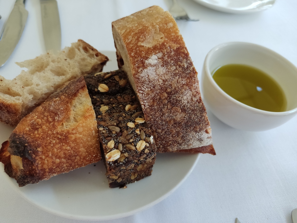 A plate with four different types of bread and a little dish of oil