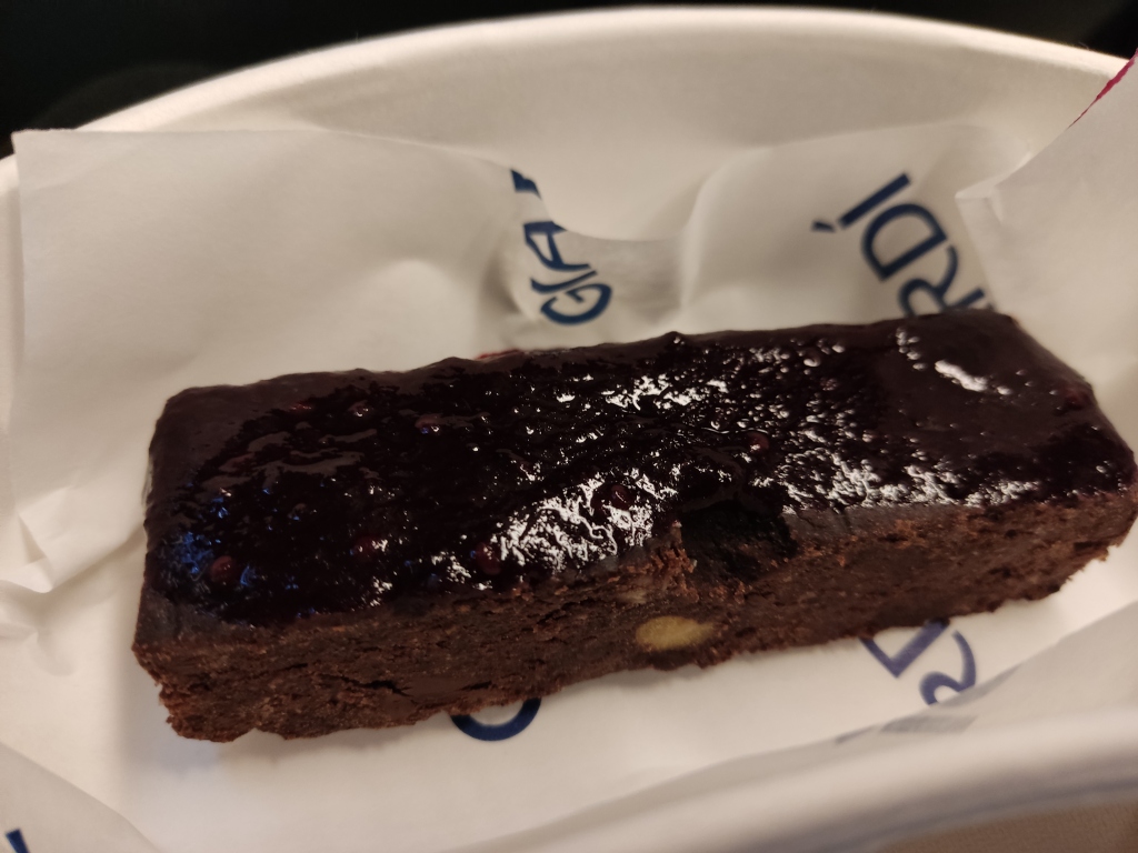 A dense looking brownie slice, topped with fruity jam