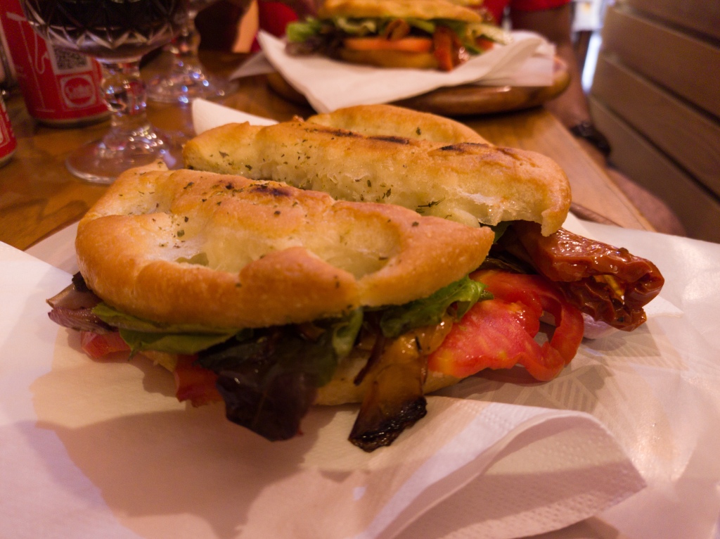 A round focaccia filled with roasted vegetables and lettuce leaves