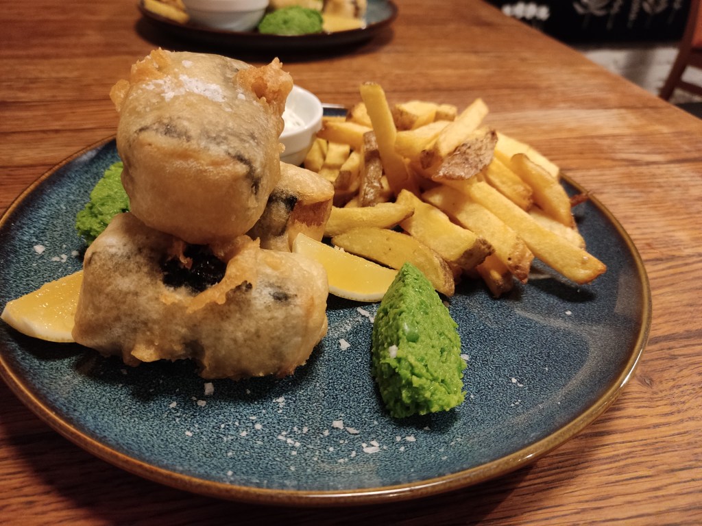 Three small blocks of tofish, a pile of chips, and some pea puree.