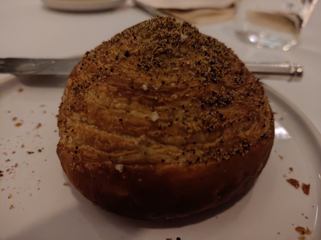 A bread bun with lots of exquisite looking layers and plenty of seasoning on top