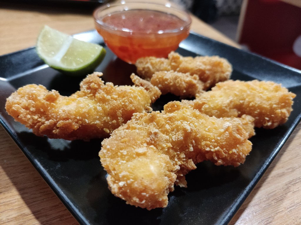 Four crispy tempura prawns with a wedge of lime and a pot of sweet chilli dipping sauce