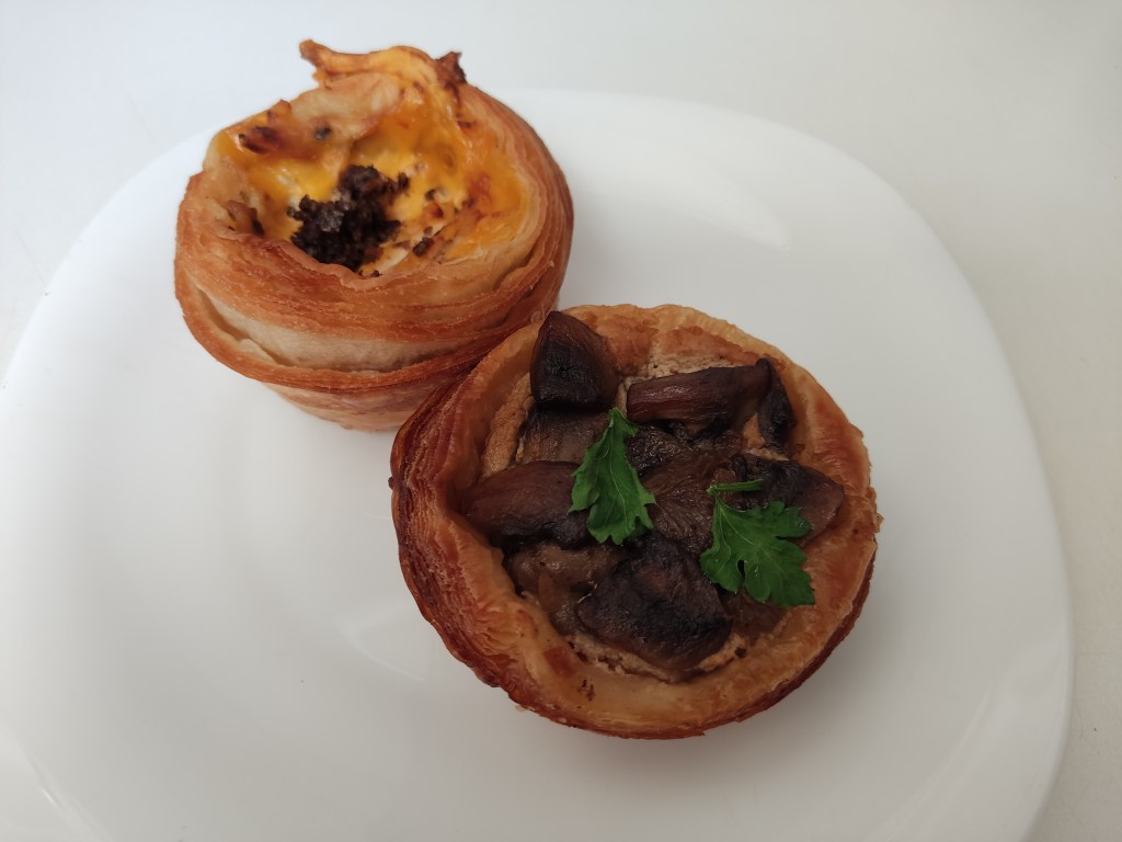 Two small round savoury tarts, one with a cheesy filling the other mushroom 