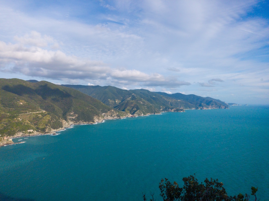 The hilly coastline of the Cinque Terre with a bright blue sea in hte foreground