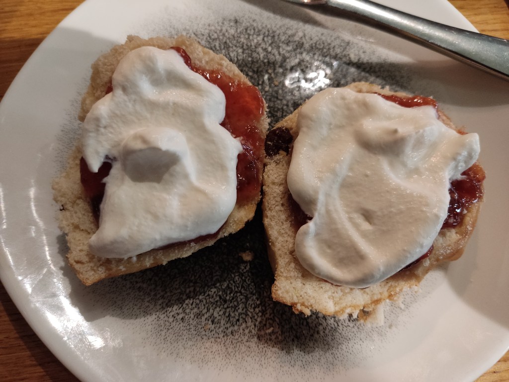 Two halves of a scone spread with cream and jam
