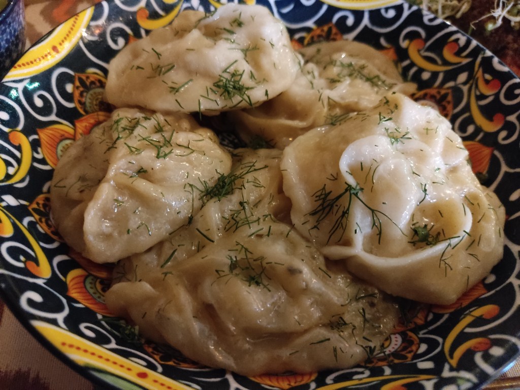 A bowl of piled up dumplings garnished with dill