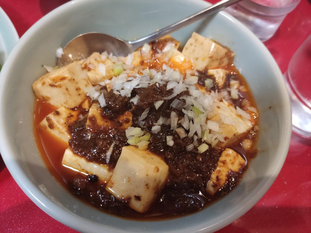 A bowl of mapo tofu with loads of silky tofu cubes poking out at the top