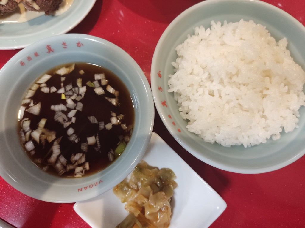 A bowl of miso soup, a small plate of pickled vegetables, and a bowl of fluffy white rice